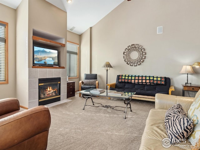 carpeted living room with high vaulted ceiling and a tile fireplace