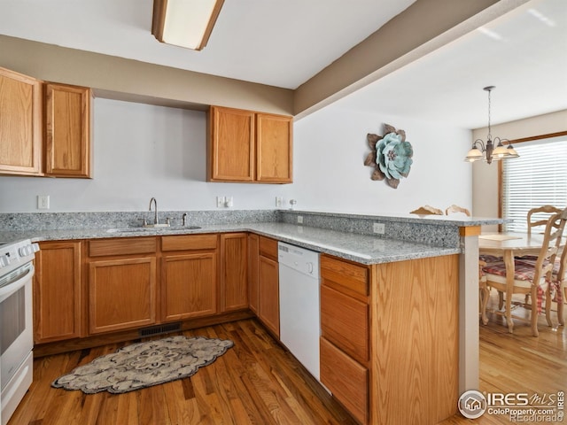 kitchen featuring pendant lighting, white appliances, sink, a notable chandelier, and kitchen peninsula