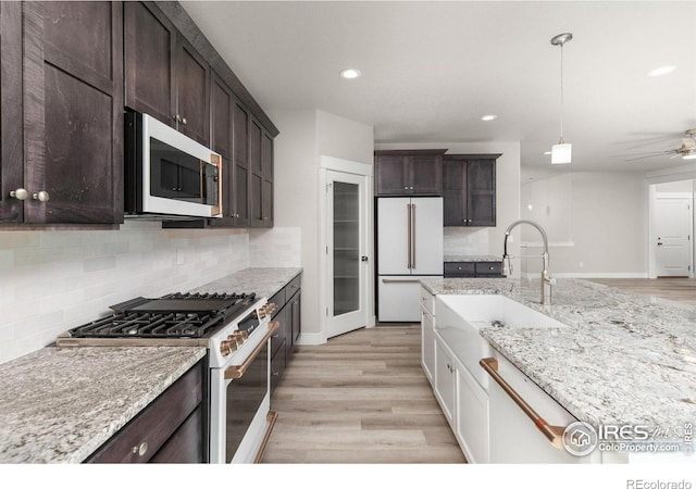 kitchen with sink, white appliances, dark brown cabinetry, decorative backsplash, and light wood-type flooring