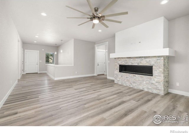 unfurnished living room featuring ceiling fan, a fireplace, and light hardwood / wood-style flooring