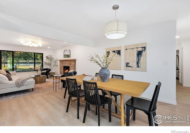 dining space featuring a fireplace and light hardwood / wood-style flooring