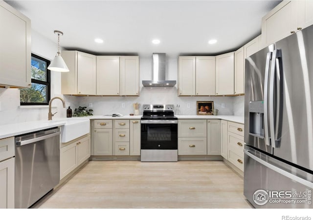 kitchen with wall chimney range hood, tasteful backsplash, light hardwood / wood-style flooring, decorative light fixtures, and appliances with stainless steel finishes