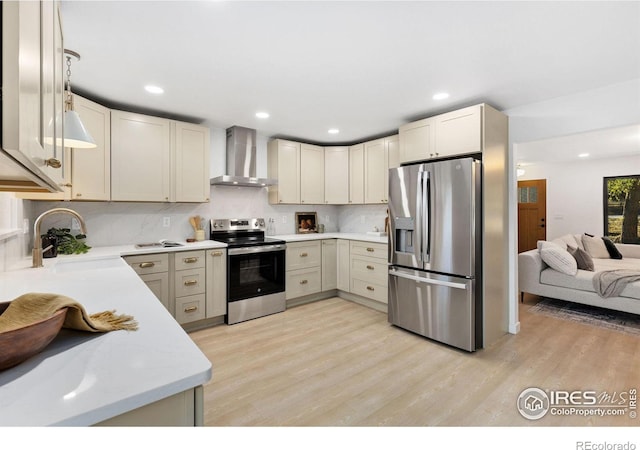 kitchen featuring wall chimney exhaust hood, light wood-type flooring, sink, and appliances with stainless steel finishes