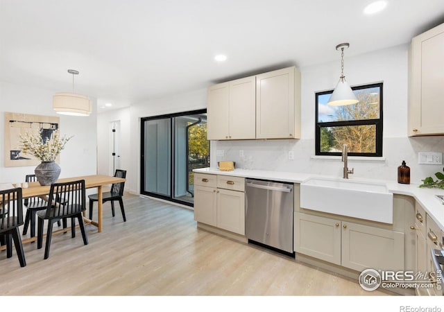 kitchen with sink, stainless steel dishwasher, decorative light fixtures, and light hardwood / wood-style floors