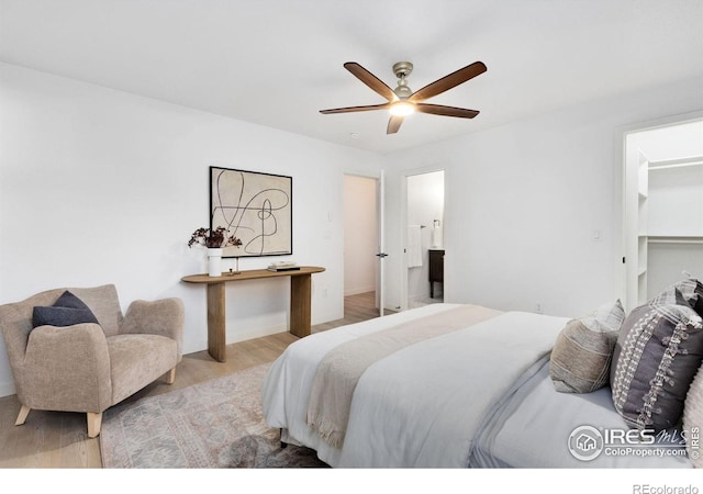 bedroom featuring ceiling fan, a spacious closet, and light hardwood / wood-style flooring