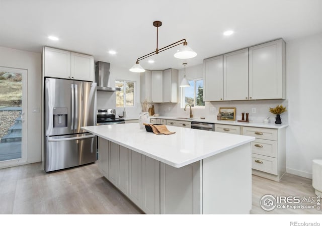 kitchen with a center island, hanging light fixtures, wall chimney exhaust hood, decorative backsplash, and stainless steel appliances