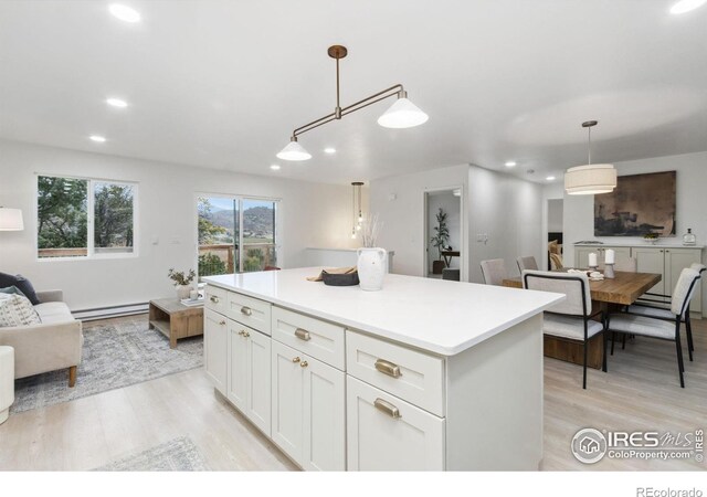 kitchen with a baseboard heating unit, light hardwood / wood-style flooring, decorative light fixtures, a kitchen island, and white cabinetry