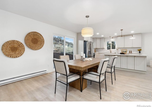 dining room featuring light hardwood / wood-style floors, a baseboard radiator, and plenty of natural light