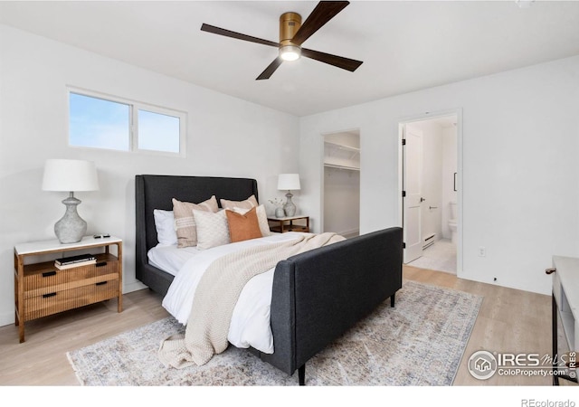 bedroom featuring ceiling fan, ensuite bathroom, light hardwood / wood-style floors, a walk in closet, and a closet