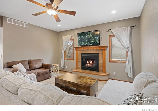 living room with ceiling fan and a tiled fireplace