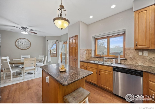 kitchen with sink, decorative light fixtures, dishwasher, a kitchen island, and decorative backsplash