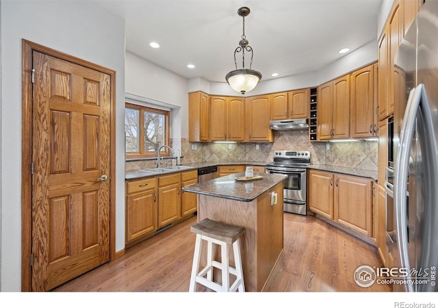 kitchen with sink, tasteful backsplash, decorative light fixtures, a center island, and appliances with stainless steel finishes