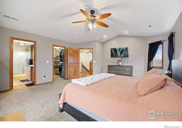 bedroom with lofted ceiling, a walk in closet, ensuite bath, a closet, and ceiling fan