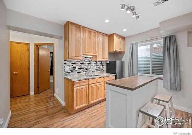 kitchen with sink, decorative backsplash, and light wood-type flooring