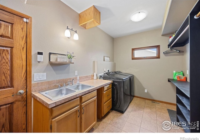 clothes washing area featuring independent washer and dryer, cabinets, and sink