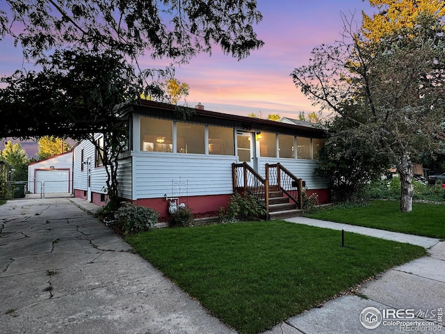 view of front of home with a garage, a yard, and an outdoor structure