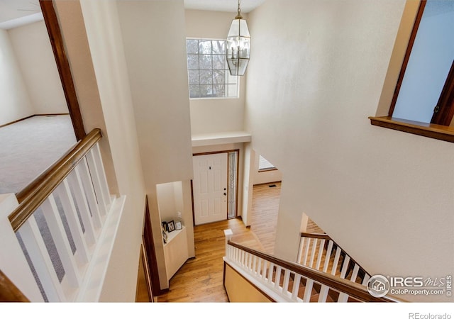 stairs with hardwood / wood-style floors and a notable chandelier