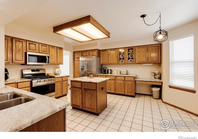 kitchen with stainless steel appliances, sink, decorative light fixtures, a center island, and light tile patterned flooring