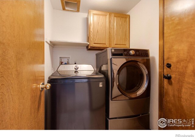 clothes washing area with cabinets and washer and dryer