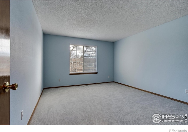 carpeted spare room featuring a textured ceiling