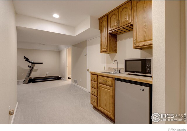 kitchen with light carpet, fridge, and sink