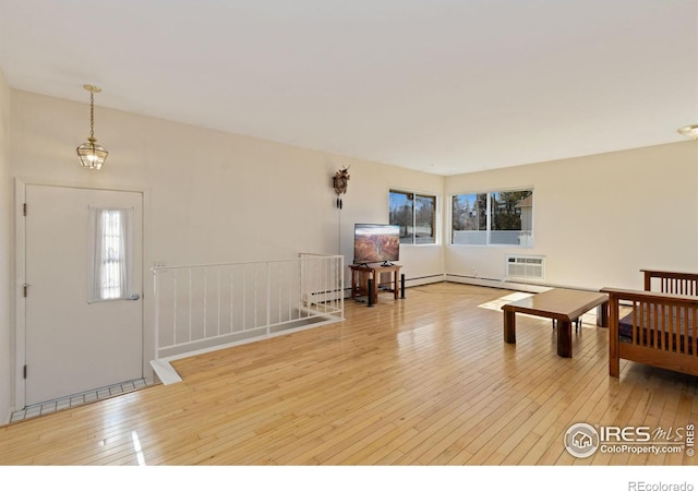 living room with baseboard heating, a wall mounted AC, and wood-type flooring