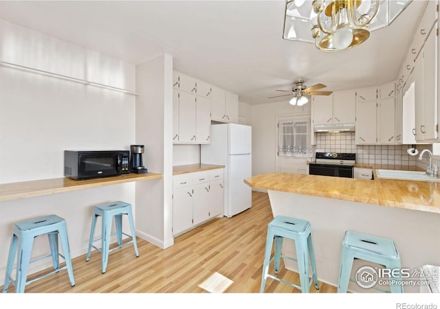 kitchen featuring kitchen peninsula, a breakfast bar, sink, electric range, and white cabinets