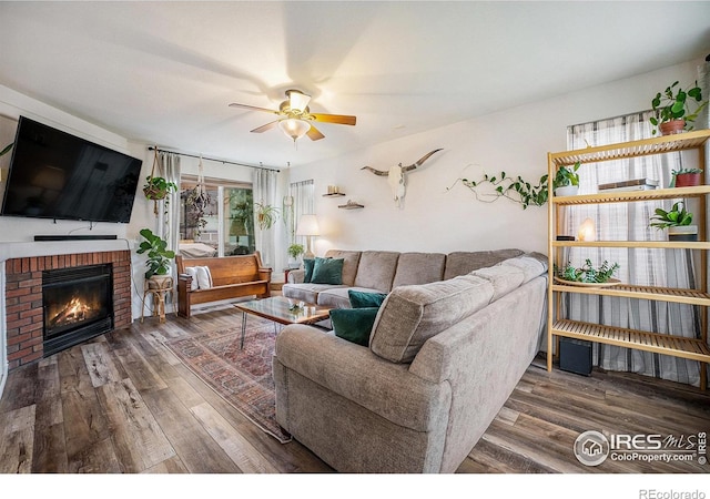 living room featuring dark hardwood / wood-style floors, ceiling fan, and a fireplace