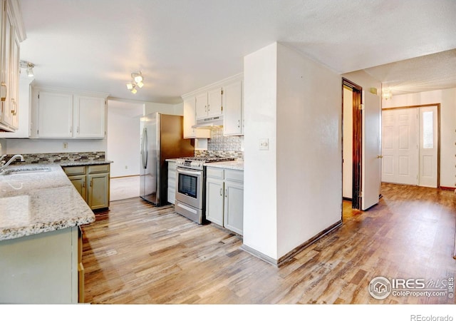 kitchen with decorative backsplash, white cabinetry, sink, and stainless steel appliances