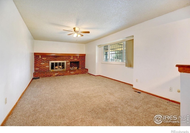 unfurnished living room featuring a textured ceiling, carpet floors, a brick fireplace, and ceiling fan