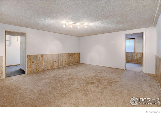 carpeted empty room with a textured ceiling and wooden walls