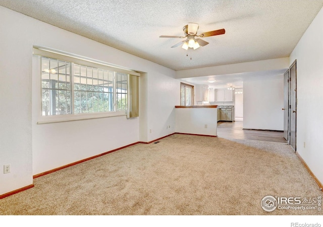 unfurnished living room with carpet, ceiling fan, and a textured ceiling