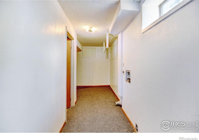 corridor featuring a textured ceiling and light colored carpet