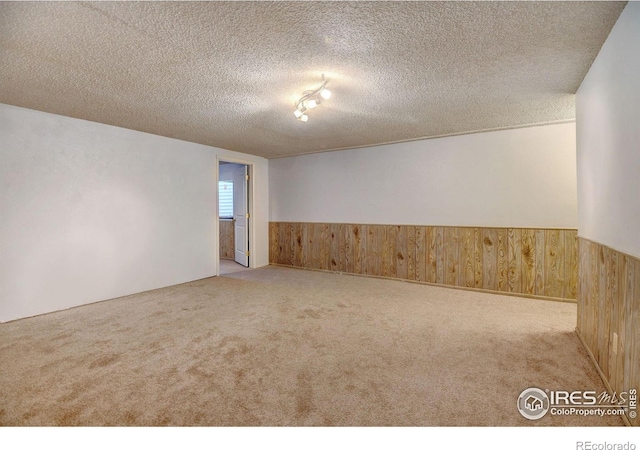 empty room with light carpet and a textured ceiling