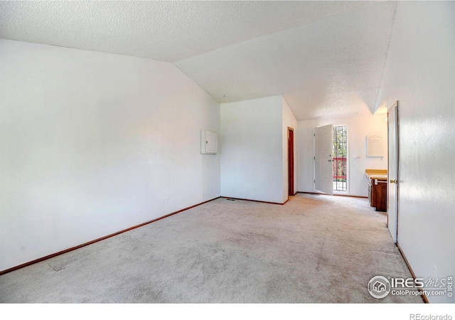 carpeted empty room featuring a textured ceiling and vaulted ceiling