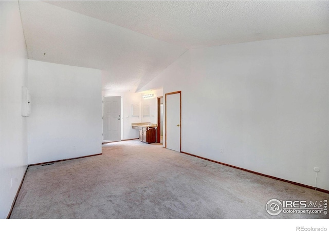 carpeted empty room featuring lofted ceiling and a textured ceiling