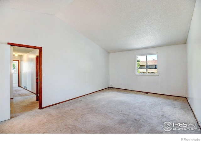 carpeted empty room with a textured ceiling and lofted ceiling