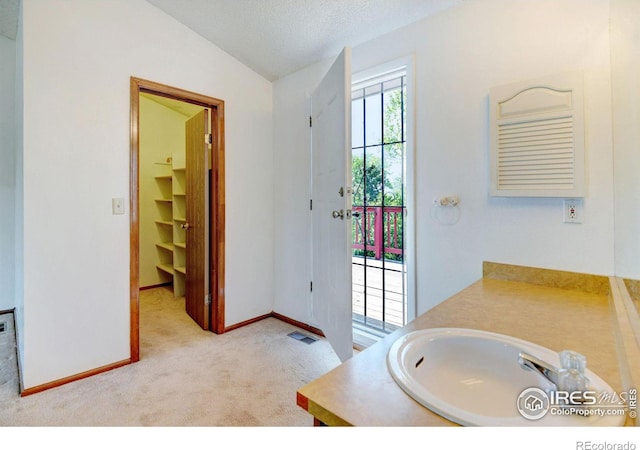 bathroom featuring a textured ceiling, vanity, and lofted ceiling