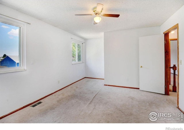 carpeted spare room featuring ceiling fan, a healthy amount of sunlight, and a textured ceiling