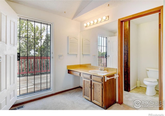 bathroom featuring a textured ceiling, vanity, toilet, and lofted ceiling