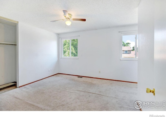 unfurnished bedroom with a textured ceiling, ceiling fan, light carpet, and a closet