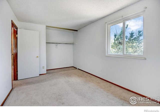 unfurnished bedroom featuring light carpet, a closet, and a textured ceiling