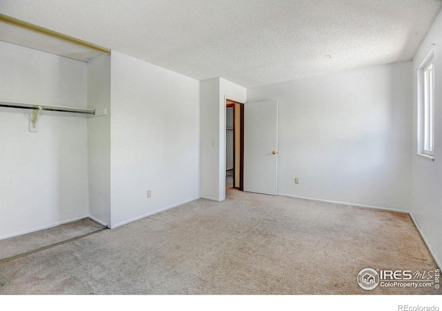 unfurnished bedroom featuring light carpet, a textured ceiling, and a closet