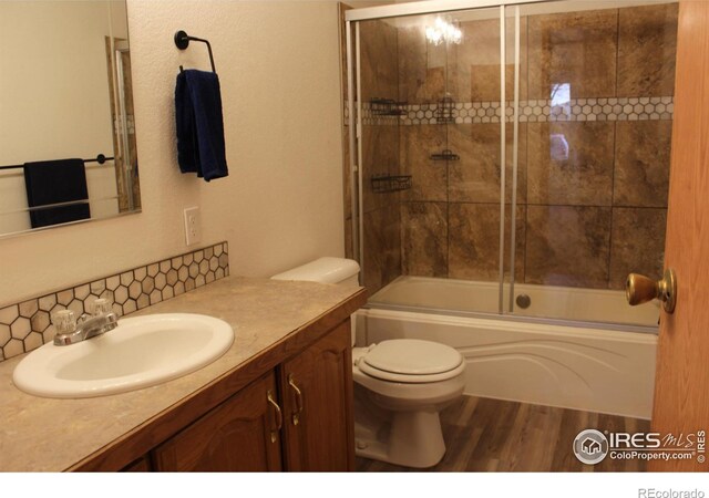 bathroom with combined bath / shower with glass door, vanity, toilet, and wood finished floors