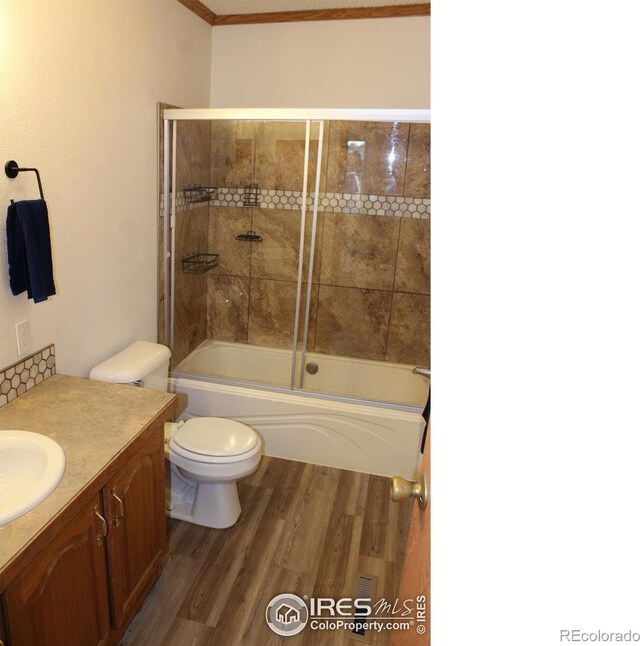 full bath featuring toilet, shower / bath combination with glass door, wood finished floors, and vanity