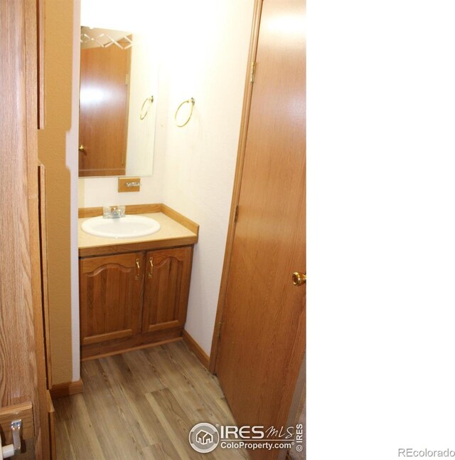 bathroom featuring vanity, baseboards, and wood finished floors