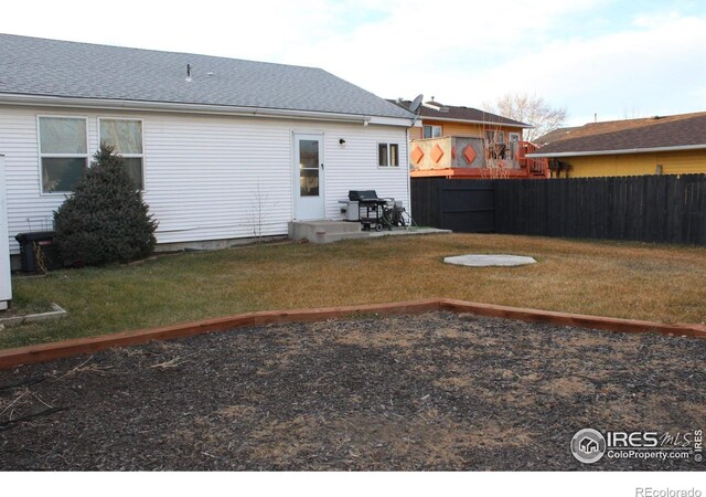 exterior space with a shingled roof, fence, and a yard