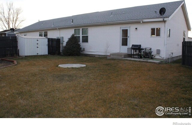 rear view of property featuring an outbuilding, fence, a storage shed, and a lawn