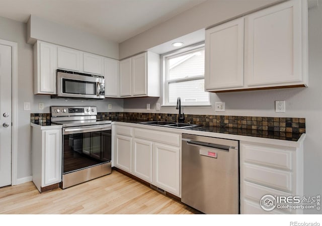 kitchen with light hardwood / wood-style floors, sink, white cabinetry, and stainless steel appliances