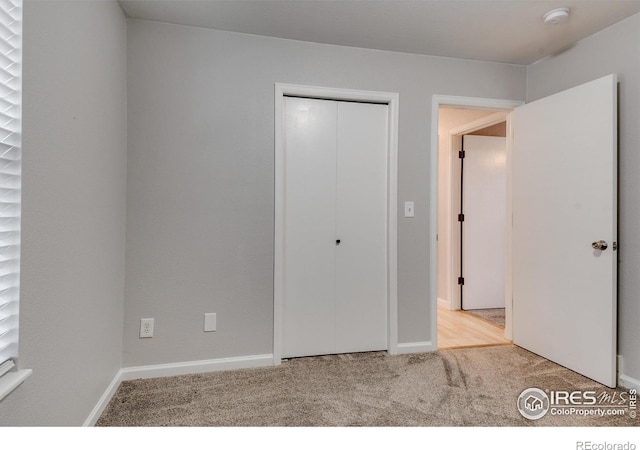 unfurnished bedroom featuring a closet and light colored carpet